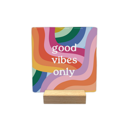 Good vibes only - Decoratie tegel - Formaat: - Op deze decoratietegel staat in het midden de Engelse tekst "good vibes only". De tegel zelf is vierkant, staat in een houten standaard en heeft een kleurrijke, psychedelische achtergrond met golvende banen in onder andere rood, oranje, geel, roze, lila, blauw en groen.&nbsp;L - Snelwenskaart