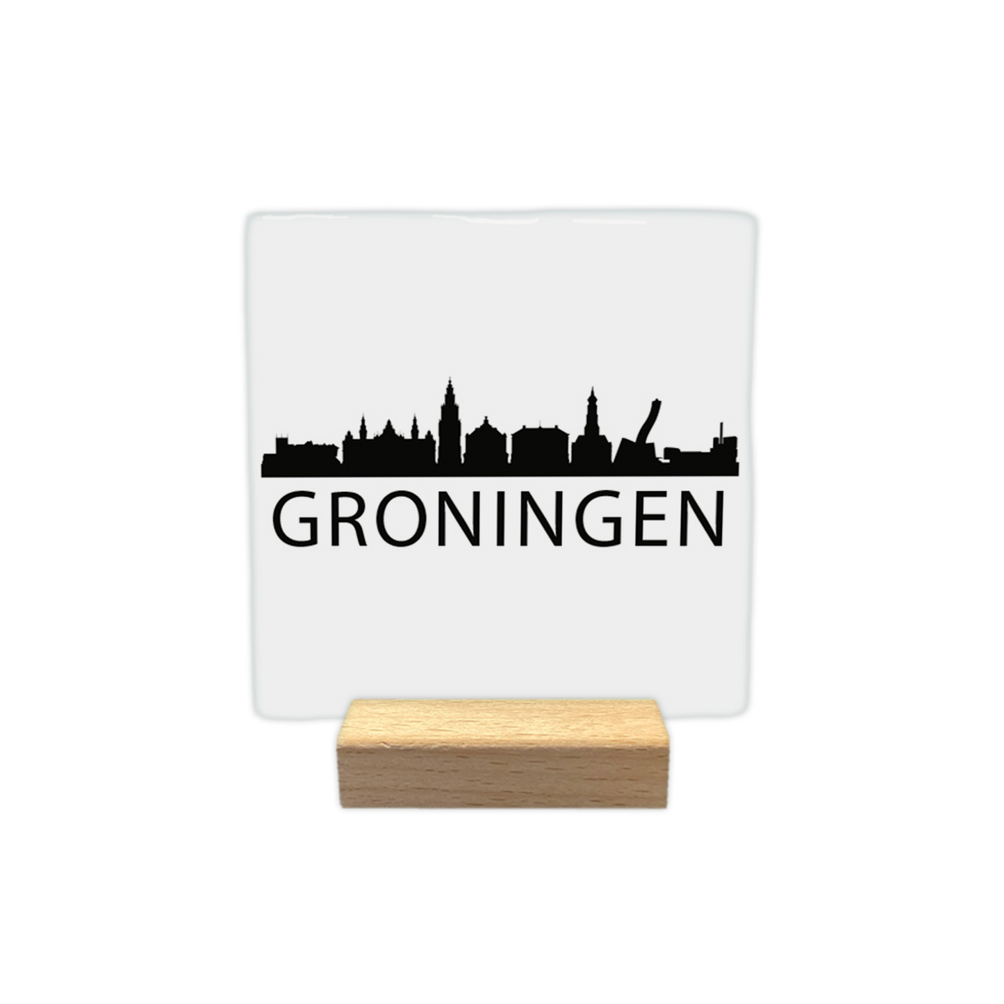 Groningen skyline - Decoratie tegel - Formaat: - Op deze decoratie tegel staat een zwarte skyline van Groningen afgebeeld tegen een witte achtergrond. Het silhouet toont diverse herkenbare gebouwen uit de stad, waaronder de Martinitoren. Onder de skyline staat in zwarte letters de plaatsnaam Groningen. Het gehele ontwerp is uitgevoerd in een minimalistische zwart-witstijl. - Snelwenskaart