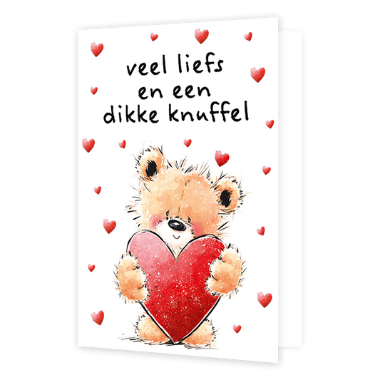 Veel liefs en een dikke knuffel - Formaat: Klein - Vorm: Staand - Liefdeskaart - Op deze wenskaart staat een pluizige teddybeer afgebeeld die een groot, glinsterend rood hart vasthoudt. De achtergrond is wit en is versierd met meerdere kleine, rode hartjes die om de beer heen zweven. Bovenaan staat in zwarte, handgeschreven letters de tekst "veel liefs en een dikke knuffel". De gehele illustratie heeft een zachte, warme uitstraling. - Snelwenskaart