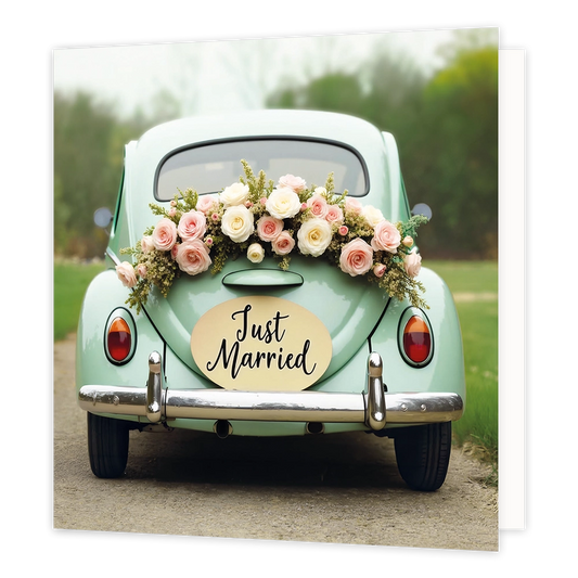 Just married - Formaat: Standaard - Vorm: Vierkant - Huwelijkskaart - Op deze wenskaart is een vintage lichtgroene auto te zien, geparkeerd op een landweggetje. De achterkant van de auto is versierd met een bloemstuk bestaande uit witte en lichtroze rozen. Boven de chromen bumper hangt een ovaal bord met de tekst "Just Married" in zwarte letters. Op de achtergrond is een onscherpe weergave van bomen en gras te zien. - Snelwenskaart