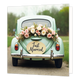 Just married - Formaat: Standaard - Vorm: Vierkant - Huwelijkskaart - Op deze wenskaart is een vintage lichtgroene auto te zien, geparkeerd op een landweggetje. De achterkant van de auto is versierd met een bloemstuk bestaande uit witte en lichtroze rozen. Boven de chromen bumper hangt een ovaal bord met de tekst "Just Married" in zwarte letters. Op de achtergrond is een onscherpe weergave van bomen en gras te zien. - Snelwenskaart