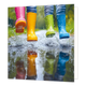 Waterplassen - Formaat: Standaard - Vorm: Vierkant - Blanco kaart - Op deze wenskaart staat een illustratie van vier gekleurde regenlaarzen in de kleuren roze, geel, groen en blauw. De laarzen behoren tot personen die door een plas water springen, wat zorgt voor opspattend water en regendruppels rondom de benen. In het water beneden is een duidelijke weerspiegeling van de gekleurde laarzen te zien. Er is geen tekst op de illustratie zichtbaar. - Snelwenskaart