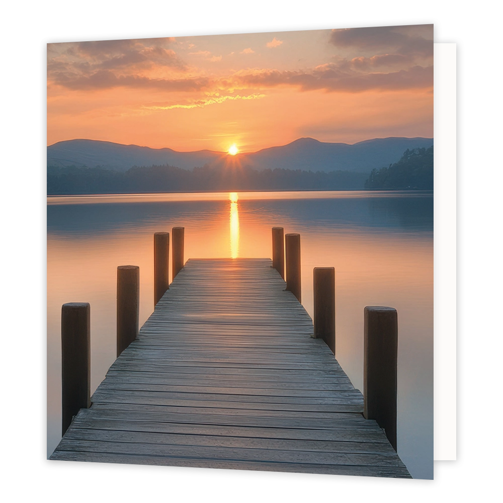 Ondergaande zon - Formaat: Standaard - Vorm: Vierkant - Blanco kaart - Op deze wenskaart staat een illustratie van een houten steiger die over een rustig wateroppervlak naar een zonsondergang of zonsopgang leidt. Aan weerszijden van de steiger steken houten palen omhoog en op de achtergrond zijn bergen en een oranjegekleurde lucht te zien. Er is geen tekst op de illustratie zichtbaar. - Snelwenskaart