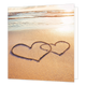 Hartjes op het strand - Formaat: Standaard - Vorm: Vierkant - Blanco kaart - Op deze wenskaart staat een illustratie van twee in elkaar geschoven harten die in het natte zand op een strand zijn getekend. De achtergrond toont de zee en het strand tijdens een warme zonsondergang of zonsopgang. Er is geen tekst op de illustratie zichtbaar. - Snelwenskaart