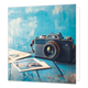 Fotocamera - Formaat: Standaard - Vorm: Vierkant - Blanco kaart - Op deze wenskaart staat een illustratie van een vintage, donkere fotocamera met een leren riem, die op een verweerde blauwe houten ondergrond ligt. Naast de camera liggen enkele oude foto's met landschappen of gebouwen, tegen een achtergrond in blauw- en wittinten. Er is geen tekst op de illustratie zichtbaar. - Snelwenskaart
