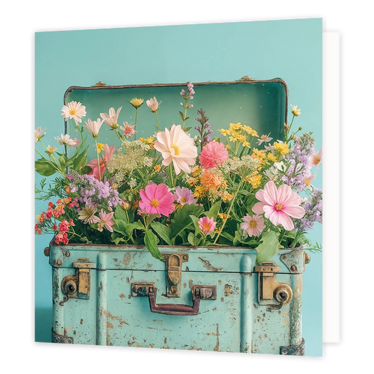 Koffer vol bloemen - Formaat: Standaard - Vorm: Vierkant - Blanco kaart - Op deze wenskaart staat een illustratie van een oude, lichtblauwe koffer die tot de rand toe gevuld is met een kleurrijke mix van diverse veldbloemen en zomerbloemen in zachte tinten zoals roze, geel en wit. De koffer heeft een vintage uitstraling met messingkleurige details en slijtageplekken, en staat afgebeeld tegen een effen lichtblauwe achtergrond. Er is geen tekst op de illustratie zichtbaar. - Snelwenskaart