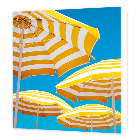 Parasols - Formaat: Standaard - Vorm: Vierkant - Blanco kaart - Op deze wenskaart staat een illustratie van vier gele en witte gestreepte parasols die van onderen tegen een helderblauwe lucht aan worden gekeken. De parasols hebben een vrolijk streepjespatroon en steken met hun stelen de lucht in. Er is geen tekst op de illustratie zichtbaar. - Snelwenskaart