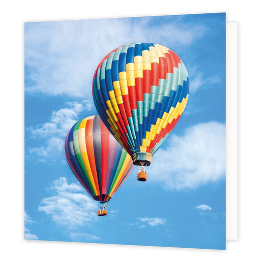 Luchtballonnen - Formaat: Standaard - Vorm: Vierkant - Blanco kaart - Op deze wenskaart staat een illustratie van twee kleurrijke hete-luchtballonnen die vliegen tegen een helderblauwe lucht met witte wolken. De ballon op de voorgrond is gedecoreerd met een zigzaggend patroon in diverse kleuren, terwijl de ballon erachter verticale banen in regenboogkleuren heeft. Onder beide ballonnen hangt een kleine mand. Er is geen tekst op de illustratie zichtbaar. - Snelwenskaart