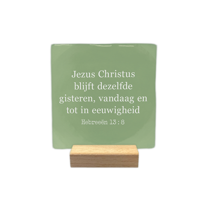 Hebreeën 13:8 - Decoratie tegel - Formaat: - Op deze decoratie tegel staat de tekst "Jezus Christus blijft dezelfde gisteren, vandaag en tot in eeuwigheid" in witte letters. Daaronder wordt de bijbeltekst "Hebreeën 13:8" vermeld. Het geheel is geplaatst tegen een zachtgroene achtergrond die een vlekkerig effect heeft. - Snelwenskaart