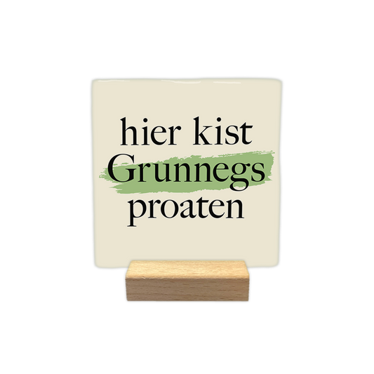 Hier kist Grunnegs proaten - Decoratie tegel - Formaat: - Op deze decoratie tegel staat de tekst "hier kist Grunnegs proaten" in zwarte letters centraal afgebeeld. Achter het woord "Grunnegs" loopt een horizontale, lichtgroene verfstreep. De achtergrond van de tegel is lichtbeige van kleur. - Snelwenskaart