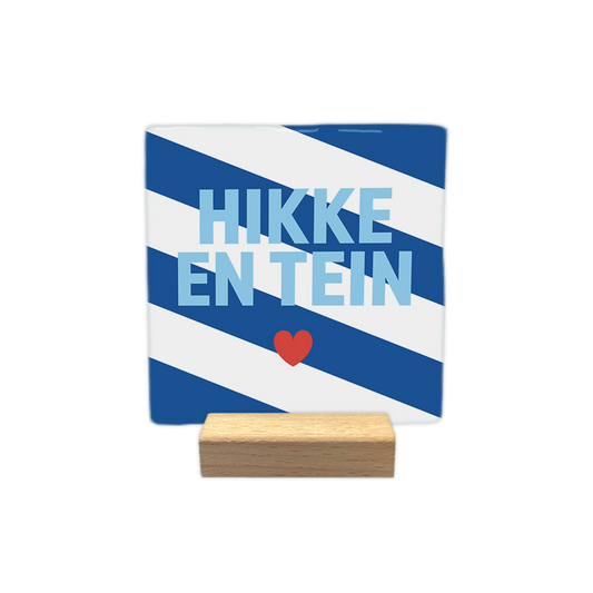 Hikke en tein - Decoratie tegel - Formaat: - Op deze decoratie tegel staat de tekst "HIKKE EN TEIN" in lichtblauwe letters centraal afgebeeld. Onder de tekst is een klein rood hartje geplaatst. De achtergrond van de tegel bestaat uit schuin lopende blauwe en witte banen. - Snelwenskaart