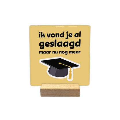 Ik vond je al geslaagd - Decoratie tegel - Formaat: - Op deze decoratie tegel staat een afstudeerhoed op een gele achtergrond. Boven de hoed staat in het zwart de tekst 'ik vond je al geslaagd maar nu nog meer'. - Snelwenskaart