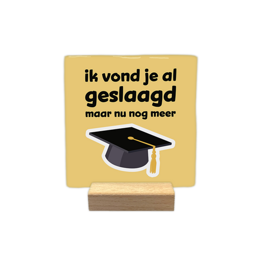 Ik vond je al geslaagd - Decoratie tegel - Formaat: - Op deze decoratie tegel staat een afstudeerhoed op een gele achtergrond. Boven de hoed staat in het zwart de tekst 'ik vond je al geslaagd maar nu nog meer'. - Snelwenskaart