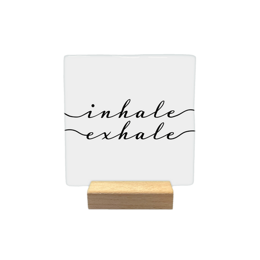 Inhale exhale - Decoratie tegel - Formaat: - Op deze decoratietegel staat de tekst "inhale" en "exhale" in zwarte letters met een elegant, cursief handschrift. Beide woorden worden aan weerszijden geaccentueerd door een golvende lijn die in de tekst overgaat. De tekst is gecentreerd op een witte achtergrond. - Snelwenskaart