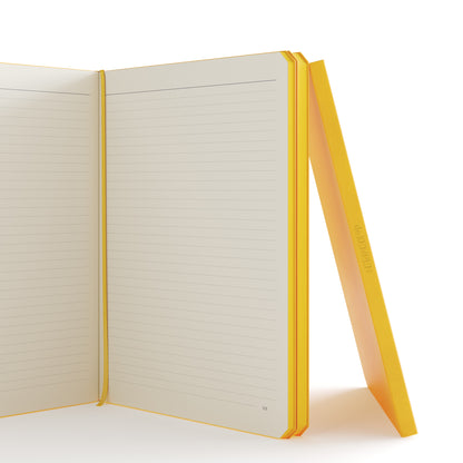 Op deze afbeelding is een opengeklapt geel notitieboek te zien waarbij zichtbaar is dat er lijnen en pagina nummer aan de binnenkant zitten