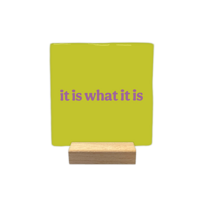 It is what it is - Decoratie tegel - Formaat: - Op deze decoratietegel staat de tekst "it is what it is" in paarse, speelse letters centraal afgebeeld. De achtergrond van de illustratie is uitgevoerd in een egale, limegroene kleur. - Snelwenskaart