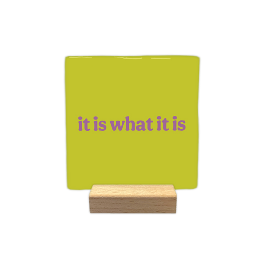 It is what it is - Decoratie tegel - Formaat: - Op deze decoratietegel staat de tekst "it is what it is" in paarse, speelse letters centraal afgebeeld. De achtergrond van de illustratie is uitgevoerd in een egale, limegroene kleur. - Snelwenskaart