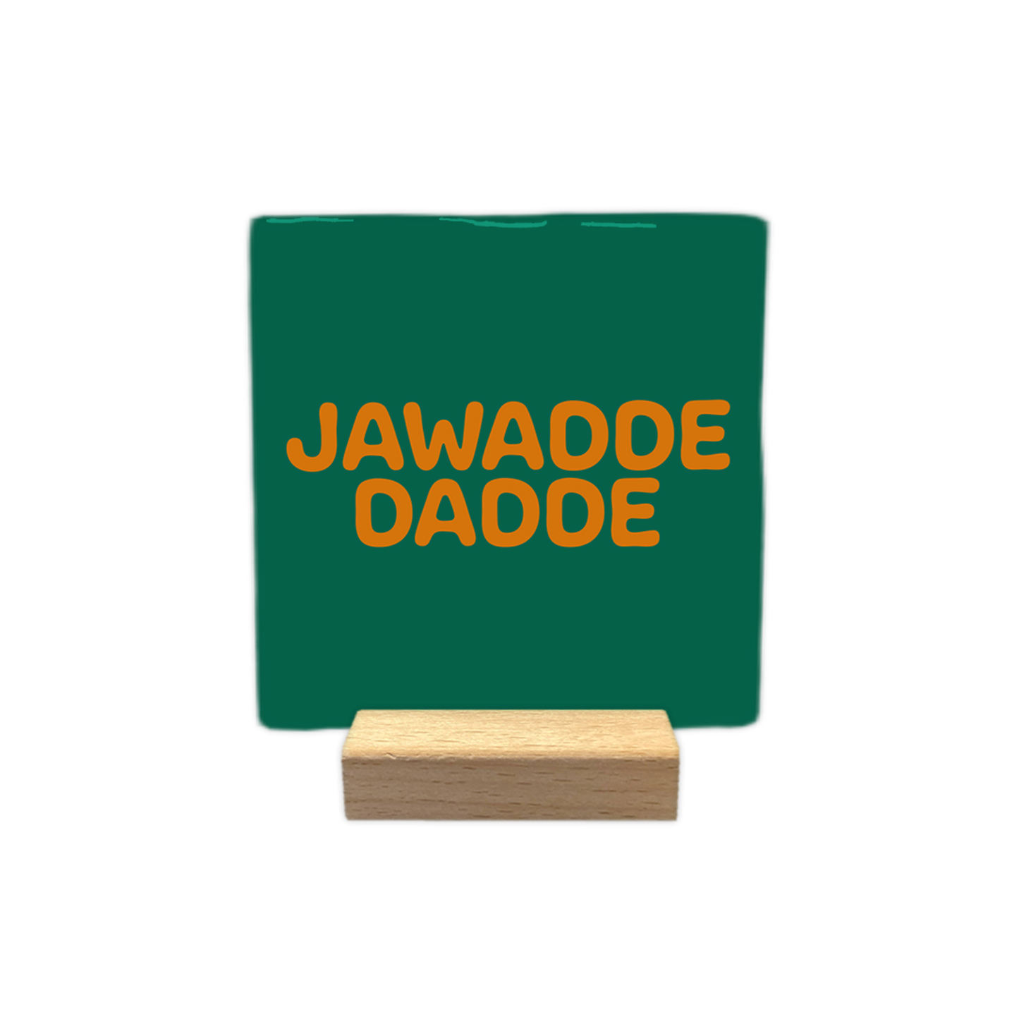 Jawadde dadde - Decoratie tegel - Formaat: - Op deze decoratie tegel staat de tekst "jawadde dadde" in twee regels afgebeeld. De tekst is geschreven in oranje, afgeronde letters. De achtergrond van de tegel is donkergroen. - Snelwenskaart