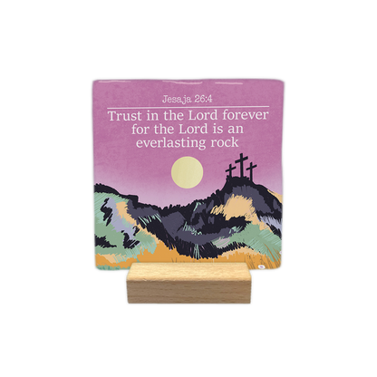 Jesaja 26:4 - Decoratie tegel - Formaat: - Op deze decoratie tegel staat bovenaan de tekst "Jesaja 26:4" en de bijbeltekst "Trust in the Lord forever for the Lord is an everlasting rock" in witte letters. De afbeelding toont een landschap met drie kruisen op een heuvel onder een roze lucht met een gele zon. Het heuvelachtige voorplan is kleurrijk vormgegeven met een getekende stijl in tinten zoals geel, groen en paars. - Snelwenskaart