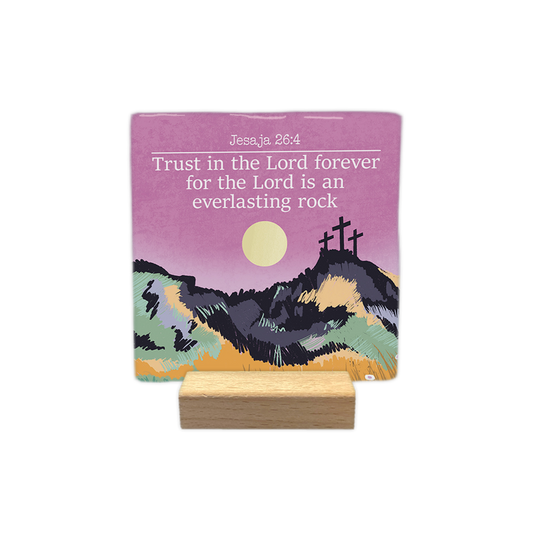 Jesaja 26:4 - Decoratie tegel - Formaat: - Op deze decoratie tegel staat bovenaan de tekst "Jesaja 26:4" en de bijbeltekst "Trust in the Lord forever for the Lord is an everlasting rock" in witte letters. De afbeelding toont een landschap met drie kruisen op een heuvel onder een roze lucht met een gele zon. Het heuvelachtige voorplan is kleurrijk vormgegeven met een getekende stijl in tinten zoals geel, groen en paars. - Snelwenskaart