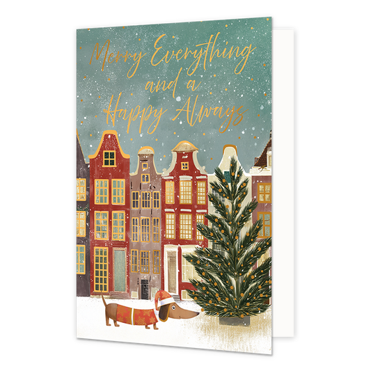Merry everything and a happy always - Formaat: Standaard - Vorm: Staand - Kerstkaart - Op deze wenskaart is een winterse stadsgezicht te zien met traditionele grachtenpandjes en een grote kerstboom op de besneeuwde voorgrond. Onderaan loopt een dachshund hondje dat een kerstmuts en een kersttrui draagt door de sneeuw. De lucht is groenblauw van kleur en gevuld met vallende sneeuwvlokken en gouden stipjes. Bovenaan de illustratie staat de goudkleurige handgeschreven tekst "Merry Everything and a Happy Alway