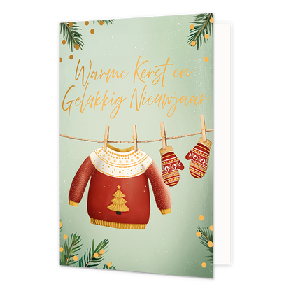 Warme kerst en gelukkig nieuwjaar - Formaat: Standaard - Vorm: Staand - Kerstkaart - Op deze wenskaart hangen een rode kersttrui en twee bijpassende wanten met houten knijpers aan een waslijn. De trui is versierd met een gouden kerstboom op de borst en een wit patroon met hartjes bij de hals. De achtergrond heeft een zachte groene kleur, omlijst met dennentakken en gouden stippen. Bovenaan de illustratie staat de gele, handgeschreven tekst "Warme Kerst en Gelukkig Nieuwjaar". - Snelwenskaart