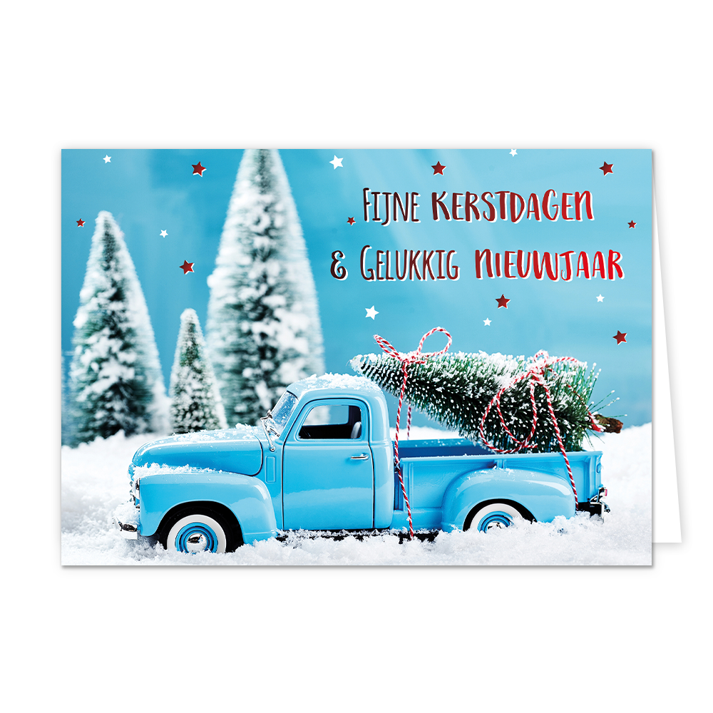Fijne kerstdagen & gelukkig nieuwjaar - 8 stuks - Formaat: Normaal - Vorm: Liggend - Kerstkaart - Op deze wenskaart staat een sfeervolle afbeelding van een lichtblauwe oldtimer pick-up truck die door een dik pak sneeuw rijdt. In de laadbak van de truck ligt een besneeuwde kerstboom, vastgebonden met een rood-wit gestreept touw. De achtergrond toont een winters landschap met wazige, besneeuwde dennenbomen onder een helderblauwe lucht die versierd is met kleine rode en witte sterretjes. Rechtsboven staat de 