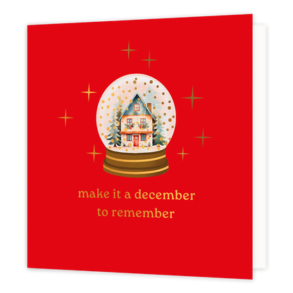 Make it a december to remember - Formaat: Normaal - Vorm: Vierkant - Kerstkaart - Op deze wenskaart staat een sfeervolle illustratie van een sneeuwbol met daarin een gezellig, besneeuwd huisje omringd door dennenbomen. In plaats van witte sneeuw dwarrelen er feestelijke goudkleurige stipjes rond in de bol. De sneeuwbol staat centraal tegen een helderrode achtergrond en wordt omringd door fonkelende gouden sterren. Onderaan de kaart staat in elegante gouden letters de inspirerende tekst "make it a december 