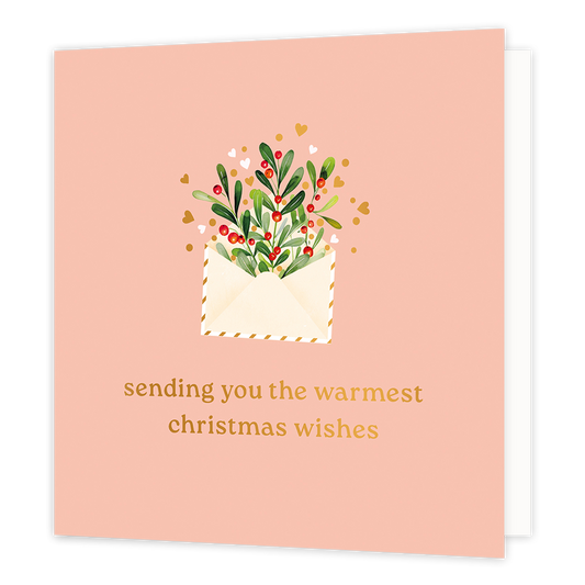 Op deze wenskaart staat een charmante illustratie van een geopende envelop waaruit een boeket van winterse groene takjes met rode besjes tevoorschijn komt. De scène is versierd met kleine witte en goudkleurige hartjes en stipjes tegen een zachte, zalmroze achtergrond. Onderaan de kaart staat in elegante goudkleurige letters de tekst "sending you the warmest christmas wishes".