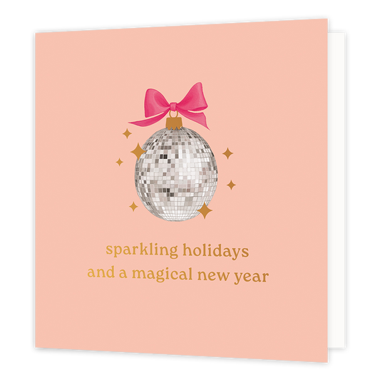 Sparkling holidays and a magical new year - Formaat: Normaal - Vorm: Vierkant - Kerstkaart - Op deze wenskaart staat een feestelijke illustratie van een discobal, die als een kerstbal is vormgegeven met een goudkleurig kroontje en een vrolijke roze strik. De discobal wordt omringd door fonkelende goudkleurige sterretjes tegen een zachte, zalmroze achtergrond. Onderaan de kaart staat in elegante goudkleurige letters de tekst "sparkling holidays and a magical new year". - Snelwenskaart