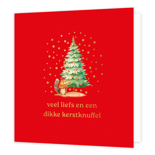 Op deze wenskaart staat een sfeervolle illustratie van een versierde kerstboom met daarnaast een schattig eekhoorntje dat een gestreepte sjaal draagt. De afbeelding is geplaatst tegen een felrode achtergrond en wordt omringd door vrolijke goudkleurige stipjes die lijken op vallende sneeuw of confetti. Onderaan de kaart staat in gouden letters de tekst "veel liefs en een dikke kerstknuffel".