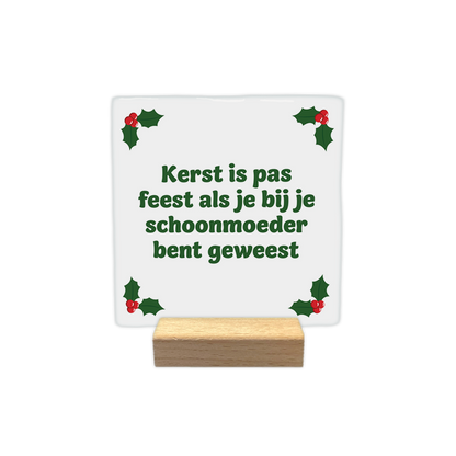 Kerst is pas feest als je bij je schoonmoeder bent geweest - Decoratie tegel - Formaat: - Op deze decoratie tegel staat een witte achtergrond met in alle vier de hoeken groene hulstblaadjes en rode bessen. In het midden staat in groene letters de tekst kerst is pas feest als je bij je schoonmoeder bent geweest. - Snelwenskaart