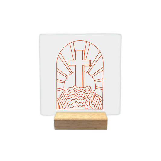 Kruis op de heuvel - Decoratie tegel - Formaat: - Op deze decoratie tegel staat een oranje lijntekening van een kruis dat boven op een heuvel is geplaatst. Achter het kruis zijn zonnestralen zichtbaar binnen een boogvormig kader. Het geheel is getekend in een eenvoudige stijl tegen een witte achtergrond. - Snelwenskaart