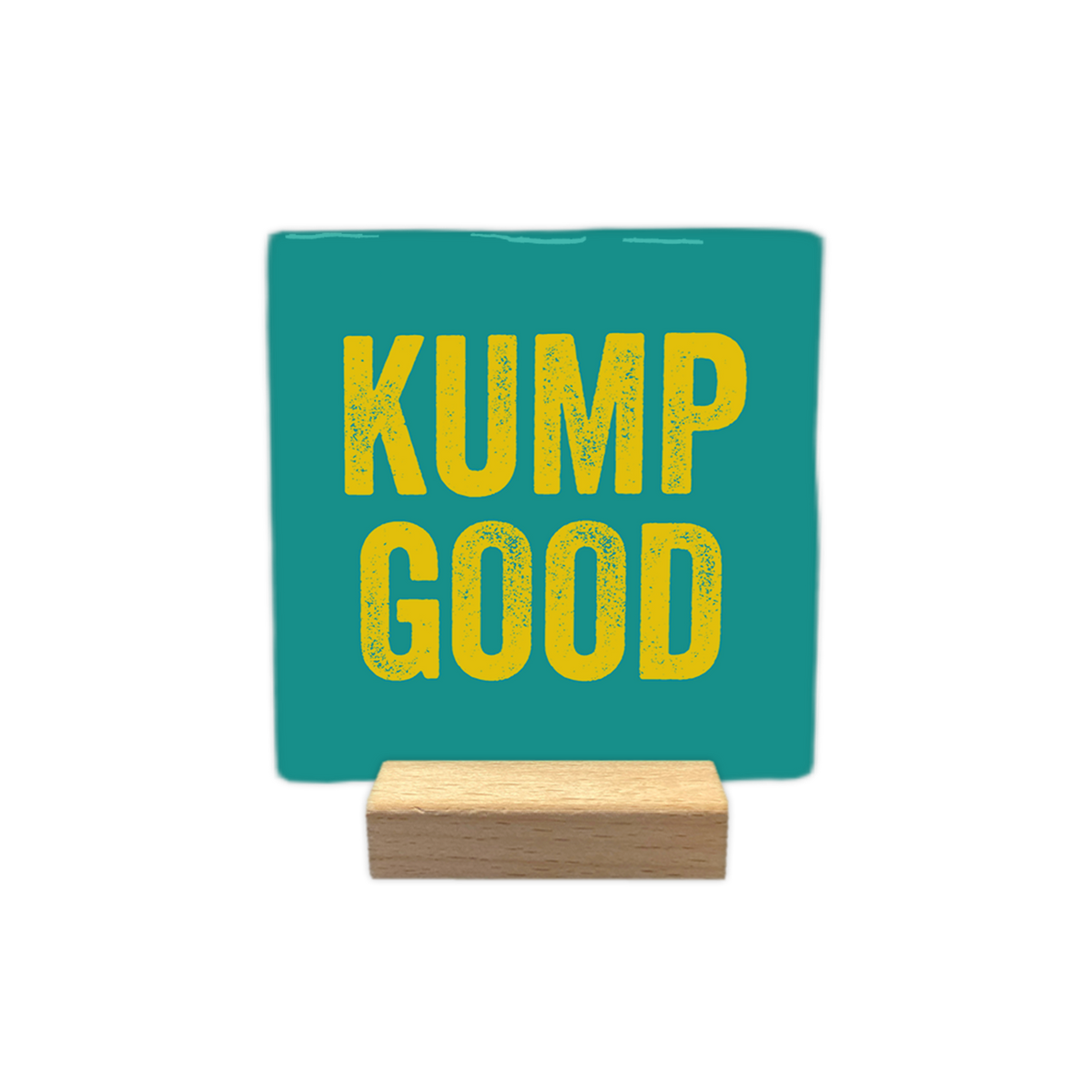 Kump Good - Decoratie tegel - Formaat: - Op deze decoratie tegel staat de tekst "kump good" in gele letters. De tekst is verdeeld over twee regels en geplaatst op een blauwgroene achtergrond. De letters hebben een textuur die eruitziet alsof ze gestempeld of verweerd zijn. - Snelwenskaart