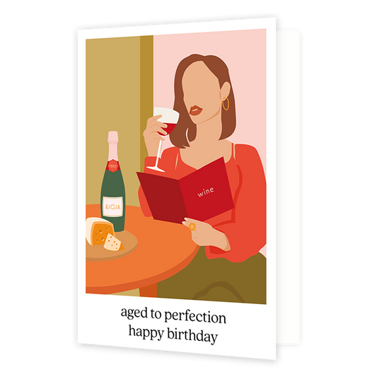Aged to perfection happy birthday - Formaat: Normaal - Vorm: Staand - Verjaardagskaart - Op deze wenskaart staat een vrouw die een glas rode wijn drinkt terwijl ze op de wijnkaart kijkt. Onder de illustratie staat de tekst: "Aged to perfection happy birthday". - Snelwenskaart