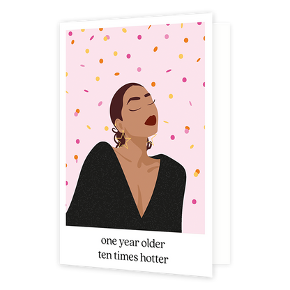 Op deze wenskaart zie je een vrouw in een zwarte glitter top en ster vormige oorbellen. De achtergrond is zacht roze met geel, roze en oranje confetti. De afbeelding staat in een witkader met onderaan de tekst 'one year older ten times hotter'. 