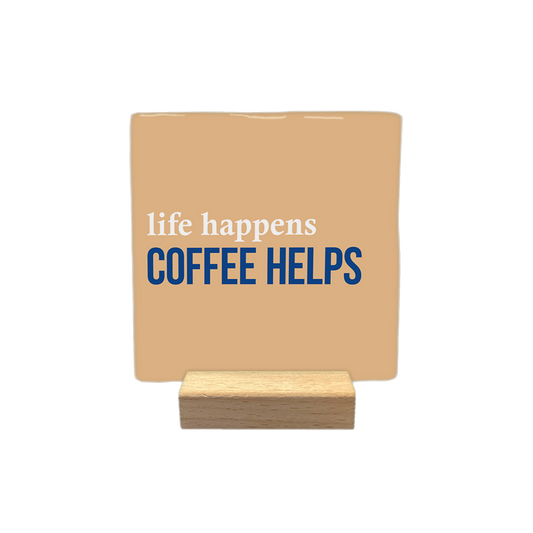 Life happens coffee helps - Decoratie tegel - Formaat: - Op deze decoratietegel staat de tekst "life happens" in witte letters bovenaan, met daaronder in grotere, donkerblauwe hoofdletters "COFFEE HELPS". Het ontwerp is gecentreerd op een lichtbruine achtergrond. - Snelwenskaart
