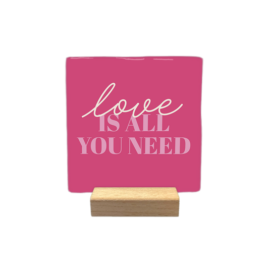 Love is all you need - Decoratie tegel - Formaat: - Op deze decoratietegel staat de tekst "love IS ALL YOU NEED" in een combinatie van sierlijke letters voor het woord "love" en strakke hoofdletters voor de rest. De tekst is in lichtroze uitgevoerd en gecentraliseerd op een donkerroze achtergrond. - Snelwenskaart