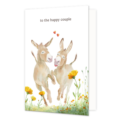 Op deze wenskaart staan twee dansende ezels. Tussen de ezels staan twee kleine rode hartjes. Midden bovenin staat in het zwart de tekst 'To the happy couple'.