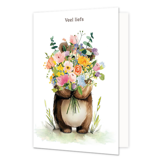 Veel liefs - Formaat: Standaard - Vorm: Staand - Blanco kaart - Op deze wenskaart staat een illustratie van een bruine beer die een groot, kleurrijk boeket veldbloemen voor zijn lichaam vasthoudt. De beer staat in een subtiel groen grasveld tegen een witte achtergrond. Bovenaan de kaart staat de tekst "Veel liefs" in kleine, donkere letters. Het geheel is uitgevoerd in een zachte, aquarelachtige stijl. - Snelwenskaart