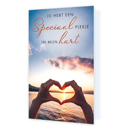 Jij hebt een speciaal plekje in mijn hart - Formaat: Standaard - Vorm: Staand - Liefdeskaart - Op deze wenskaart zie je twee handen die samen een hartvorm maken, waardoor de zon aan de horizon wordt omlijst. Boven de handen staat de tekst "JIJ HEBT EEN Speciaal PLEKJE IN MIJN hart" in een combinatie van strakke en sierlijke oranje letters. De achtergrond toont een rustig wateroppervlak met bergen in de verte en een warme, gekleurde lucht. Het geheel straalt een persoonlijke en liefdevolle boodschap uit. - 