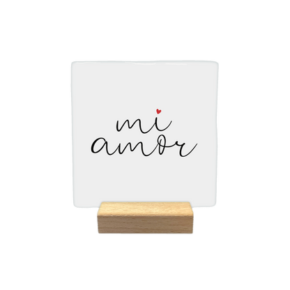 Mi amor - Decoratie tegel - Formaat: - Op deze decoratietegel staat de tekst "mi amor" in een zwart, cursief handschrift. Boven de letter "i" staat een klein, rood hartje. De tekst is gecentreerd op een witte achtergrond. - Snelwenskaart