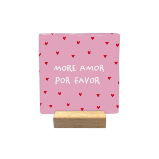 More amor por favor - Decoratie tegel - Formaat: - Op deze decoratie tegel staat de tekst "MORE AMOR POR FAVOR" in witte, handgeschreven letters centraal afgebeeld. De achtergrond is lichtroze en is versierd met een herhalend patroon van kleine, rode hartjes. - Snelwenskaart