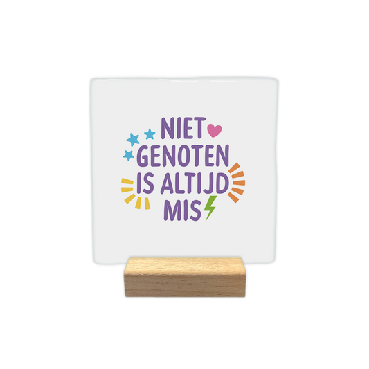 Niet genoten is altijd mis - Decoratie tegel - Formaat: - Op deze decoratie tegel staat in het paars de tekst 'Niet genoten is altijd mis'. Om de tekst heen staan verschillende vormen in verschillend kleuren. - Snelwenskaart