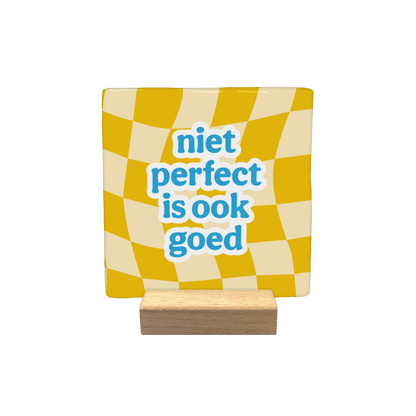 Niet perfect is ook goed - Decoratie tegel - Formaat: - Op deze decoratie tegel staat centraal de tekst "niet perfect is ook goed" in blauwe, speelse letters met een witte omlijning. De achtergrond bestaat uit een golvend schaakbordpatroon met afwisselend gele en crèmekleurige vlakken. - Snelwenskaart