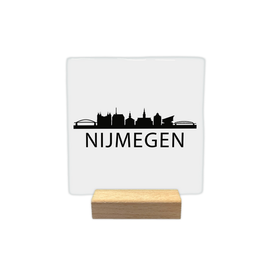 Nijmegen skyline - Decoratie tegel - Formaat: - Op deze decoratie tegel staat bovenaan een zwart silhouet van de stad Nijmegen, inclusief de Waalbrug en verschillende bekende gebouwen. Daaronder staat in grote, zwarte letters de tekst "nijmegen". Het gehele ontwerp is afgebeeld op een witte achtergrond. - Snelwenskaart