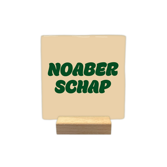 Noaberschap - Decoratie tegel - Formaat: - Op deze decoratie tegel staat de tekst "noaber schap" in donkergroene, golvende letters verdeeld over twee regels. Het ontwerp is geplaatst op een egale, lichtbeige achtergrond. - Snelwenskaart