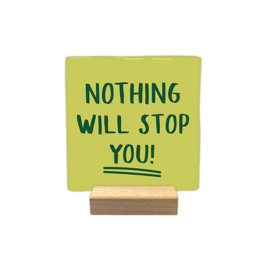 Nothing will stop you! - Decoratie tegel - Op deze wenskaart staat een vierkante, lichtgroene decoratietegel die in een houten standaard is geplaatst. Centraal op de tegel staat in donkergroene, handgeschreven hoofdletters de tekst "NOTHING WILL STOP YOU!" afgebeeld. Onder het woord "YOU!" zijn ter afsluiting twee dunne, donkergroene strepen getrokken. - Snelwenskaart