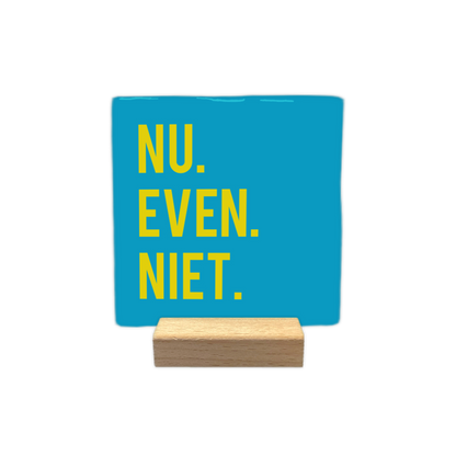 Nu even niet - Decoratie tegel - Formaat: - Op deze wenskaart is een vierkante, helderblauwe decoratietegel afgebeeld. Aan de linkerzijde van de tegel staat de tekst "NU. EVEN. NIET." geschreven in strakke, gele hoofdletters. De tekst is verdeeld over drie regels, waarbij elk woord wordt afgesloten met een duidelijke punt. - Snelwenskaart