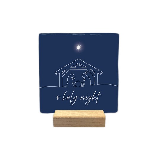 O holy night - Decoratie tegel - Formaat: - Op deze decoratie tegel staat een donkerblauwe achtergrond. In het midden is met witte lijnen een kerststal afgebeeld, met daarin de silhouetten van Maria, Jozef en het kindje Jezus in een kribbe. Boven de stal schittert een witte ster. Onderaan staat in witte sierletters de tekst o holy night. - Snelwenskaart